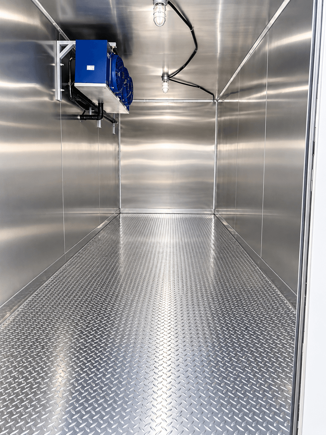 Stainless-steel refrigerated interior with a blue cooling unit and diamond-plate floor