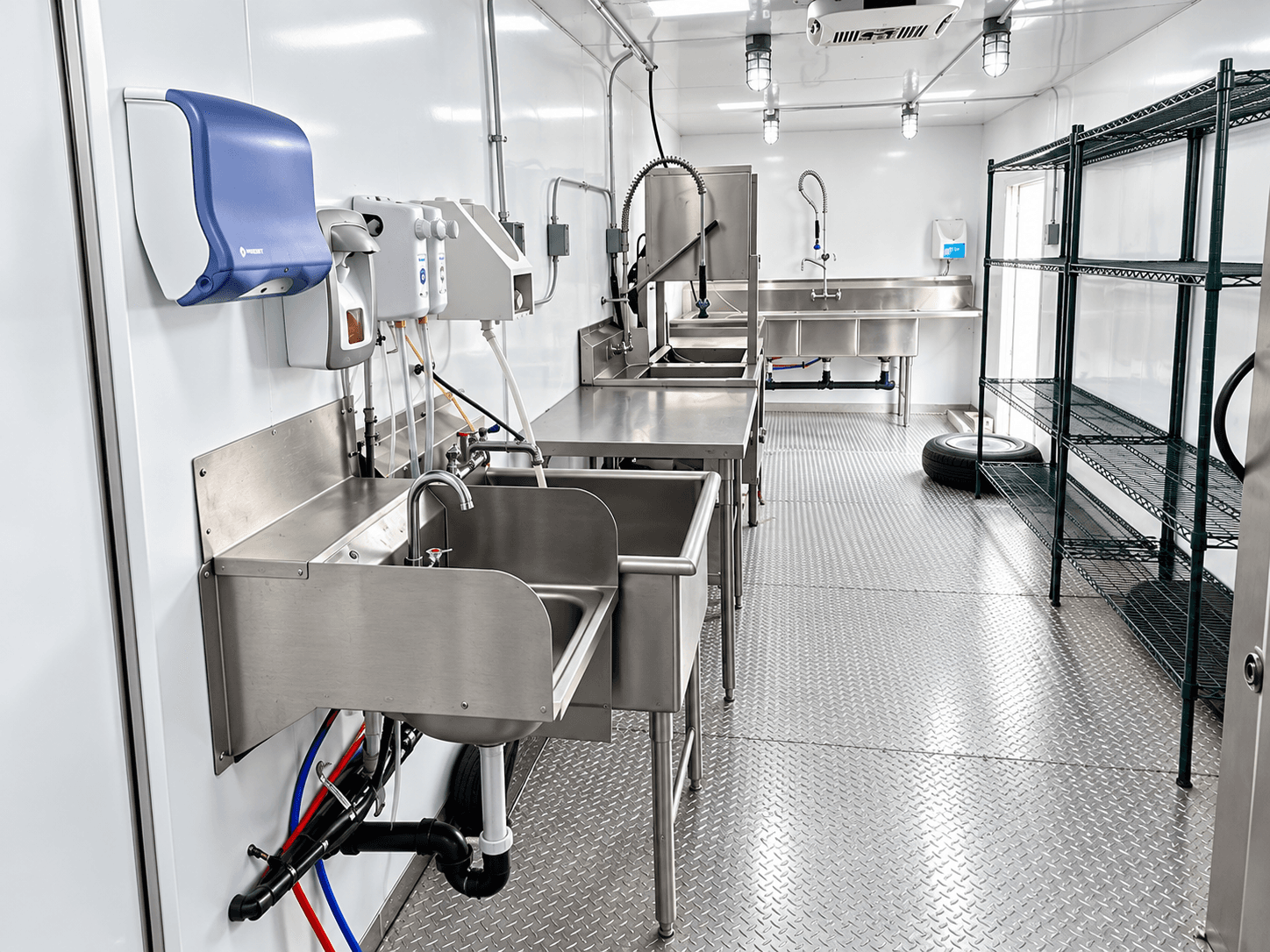 Dishwashing trailer aisle with sinks, shelving and a dishwasher