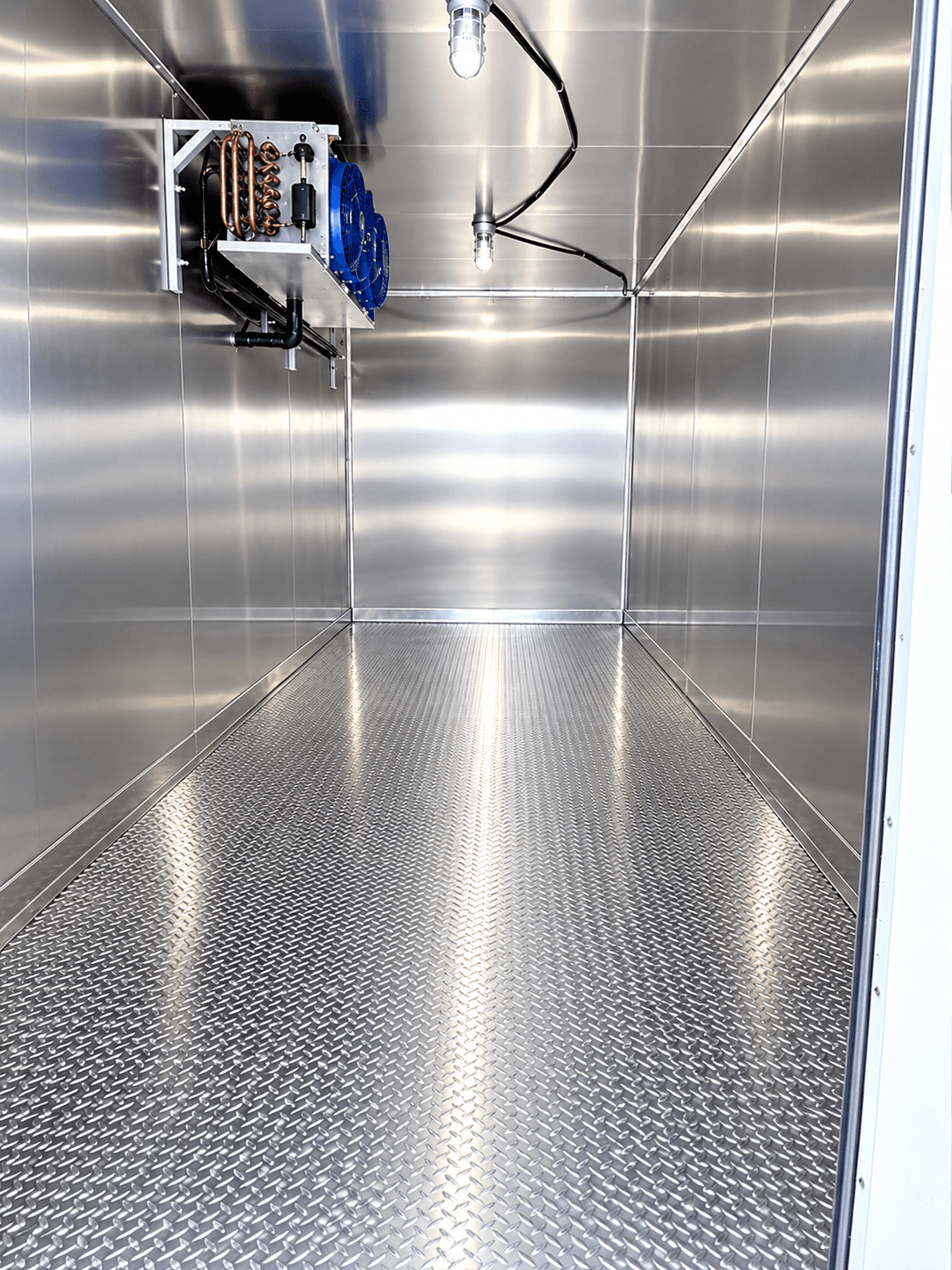 Cooling-unit fans and exposed coils inside a metal-lined refrigerated trailer